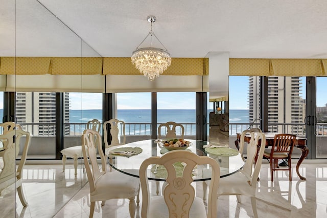 tiled dining room with a water view, a healthy amount of sunlight, a chandelier, and a textured ceiling