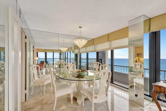 dining area with a textured ceiling, a water view, and a notable chandelier