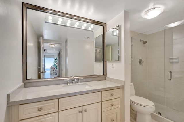 bathroom with an enclosed shower, vanity, and toilet