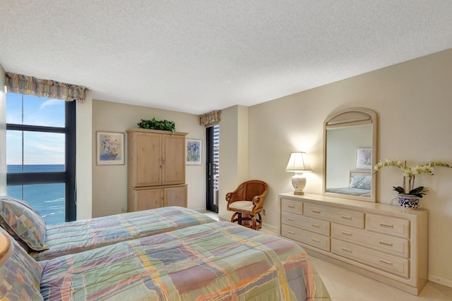 bedroom with a textured ceiling, a water view, and multiple windows