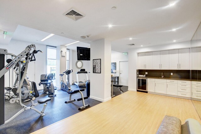 exercise room featuring wine cooler, sink, and light hardwood / wood-style flooring