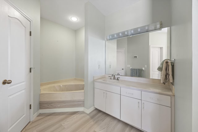 bathroom with a bathing tub, hardwood / wood-style floors, and vanity