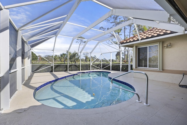 view of pool with glass enclosure and a patio area