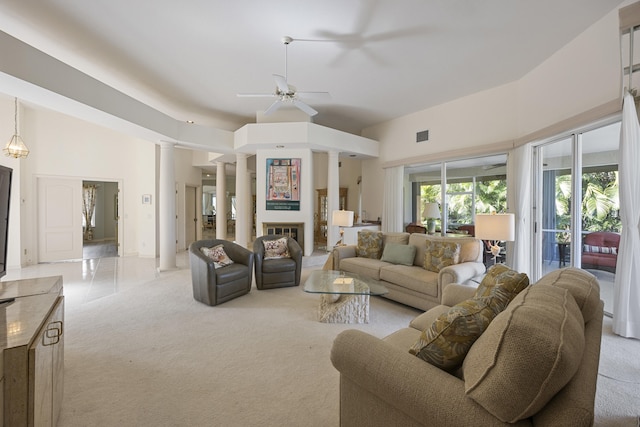 living room with ceiling fan, ornate columns, light carpet, and a towering ceiling