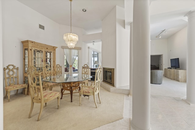 tiled dining room featuring an inviting chandelier, a high ceiling, and decorative columns