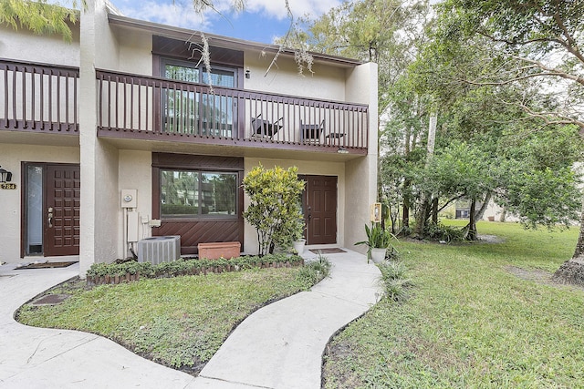 townhome / multi-family property featuring a balcony, a front yard, and central AC