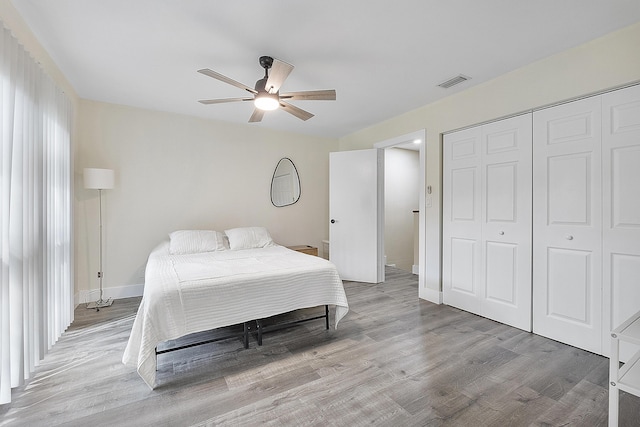 bedroom with ceiling fan, light wood-type flooring, and a closet