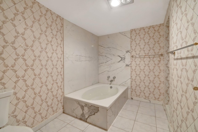 bathroom featuring toilet, tile patterned floors, and tiled tub