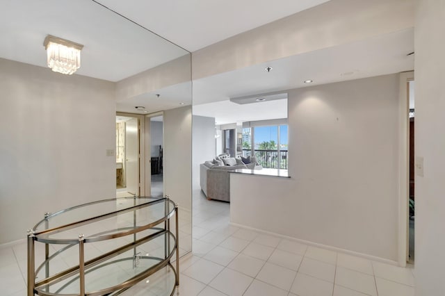 corridor featuring light tile patterned floors and an inviting chandelier