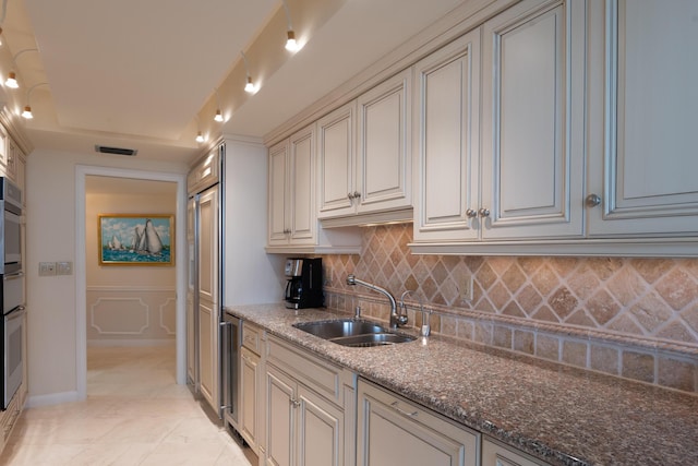 kitchen with a raised ceiling, dark stone counters, sink, oven, and tasteful backsplash