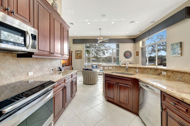 kitchen featuring light tile patterned floors, a sink, light stone countertops, stainless steel appliances, and backsplash