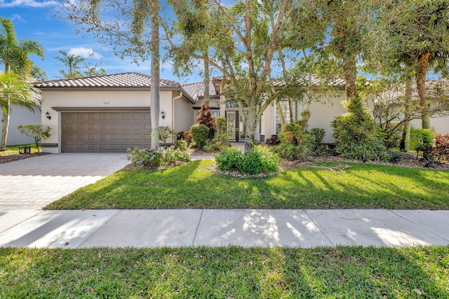 mediterranean / spanish house featuring a front lawn, decorative driveway, an attached garage, and stucco siding