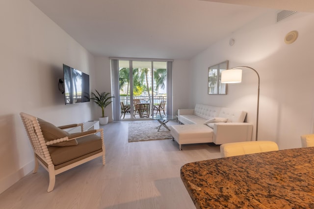 living room with expansive windows and light hardwood / wood-style flooring