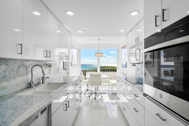 kitchen featuring stainless steel appliances, sink, pendant lighting, light tile patterned floors, and white cabinetry