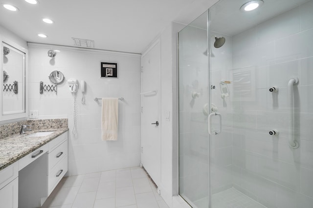 bathroom with vanity, tile patterned floors, a shower with door, and tile walls