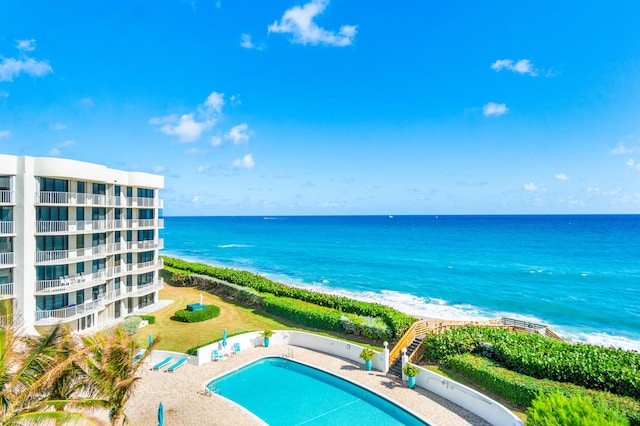 view of pool featuring a patio area, a water view, and a beach view