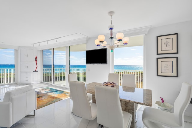 dining space with track lighting, a water view, light tile patterned floors, a notable chandelier, and a healthy amount of sunlight