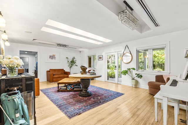 interior space with a chandelier, a healthy amount of sunlight, light hardwood / wood-style floors, and a skylight