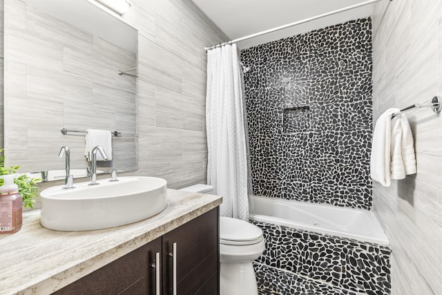 full bathroom with shower / tub combo with curtain, vanity, tile walls, and toilet