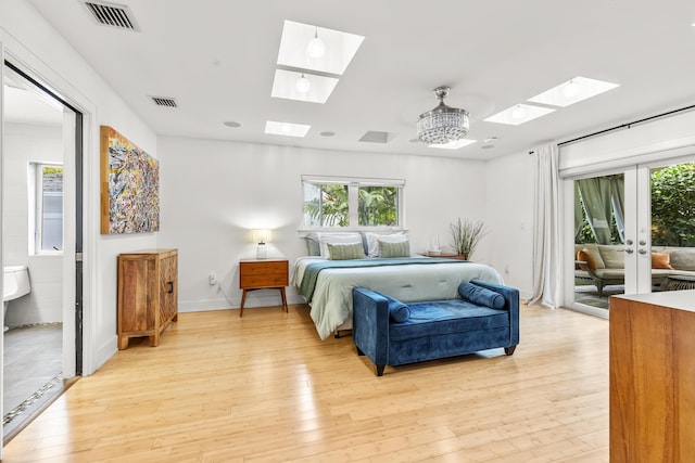 bedroom with an inviting chandelier, access to outside, light hardwood / wood-style flooring, and ensuite bathroom