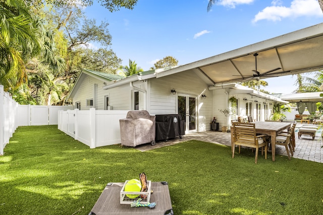 back of property featuring a yard, french doors, and a patio