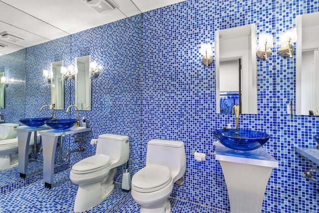 bathroom with tile patterned flooring, toilet, tile walls, and sink