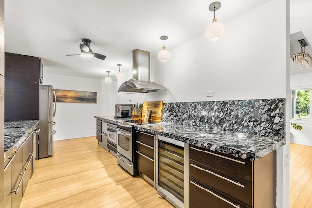 kitchen with island exhaust hood, dark stone counters, stainless steel appliances, beverage cooler, and ceiling fan