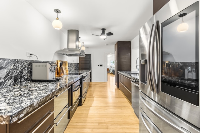 kitchen featuring island exhaust hood, decorative backsplash, dark stone countertops, and stainless steel appliances