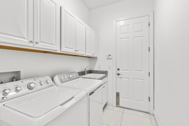 laundry area featuring sink, washing machine and dryer, light tile patterned flooring, and cabinets