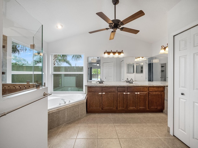 bathroom with vanity, vaulted ceiling, tiled bath, and plenty of natural light