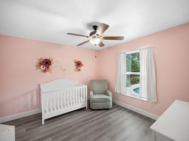 bedroom featuring a crib, hardwood / wood-style floors, and ceiling fan