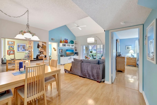 dining space featuring a textured ceiling, ceiling fan, light hardwood / wood-style flooring, and lofted ceiling