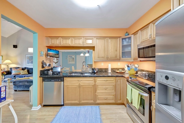 kitchen featuring dark stone countertops, sink, appliances with stainless steel finishes, and light hardwood / wood-style flooring