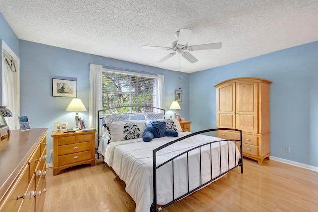 bedroom with ceiling fan, a textured ceiling, and light wood-type flooring