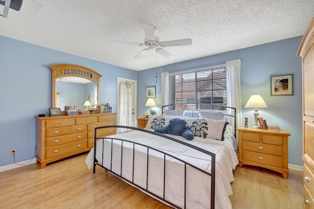 bedroom featuring ceiling fan, light wood-type flooring, and a textured ceiling