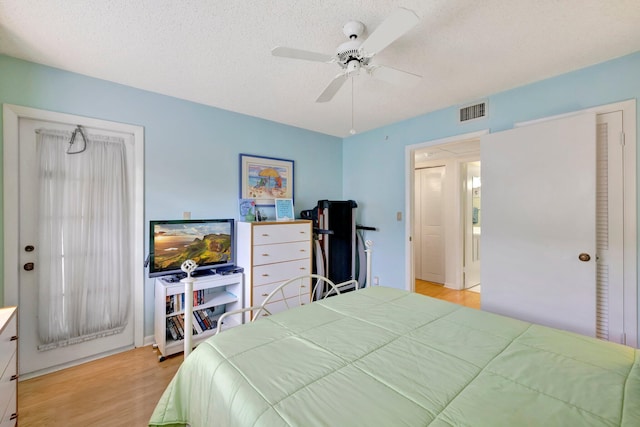 bedroom with ceiling fan, light hardwood / wood-style floors, and a textured ceiling