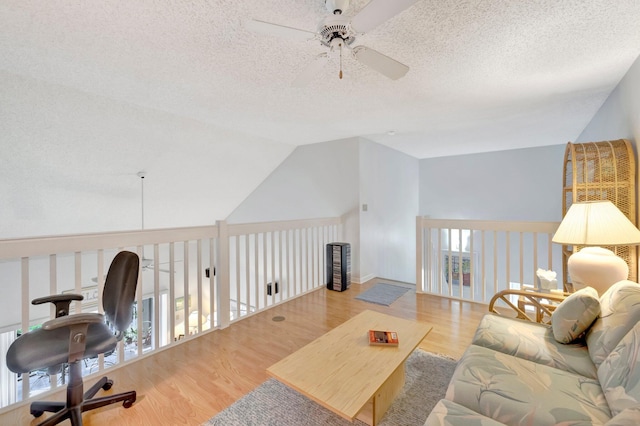 living room featuring a textured ceiling, ceiling fan, light hardwood / wood-style flooring, and lofted ceiling