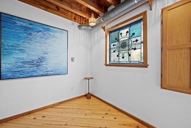 spare room with beamed ceiling, wood finished floors, and baseboards