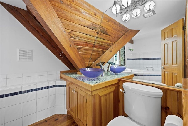 full bath with toilet, vanity, a relaxing tiled tub, and wood finished floors