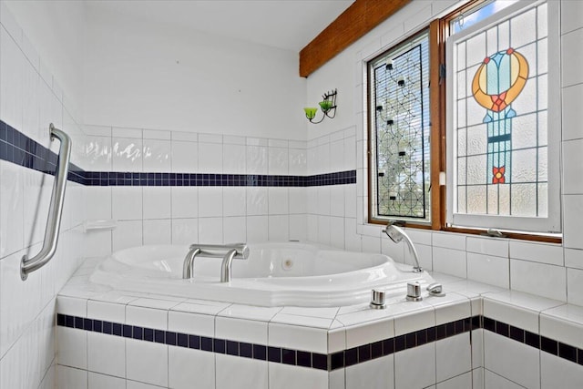 bathroom featuring beamed ceiling and a tub with jets