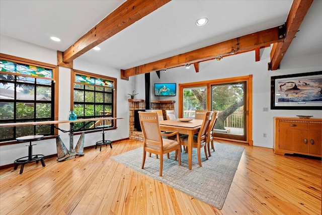 dining room featuring beam ceiling, baseboards, and light wood-style floors