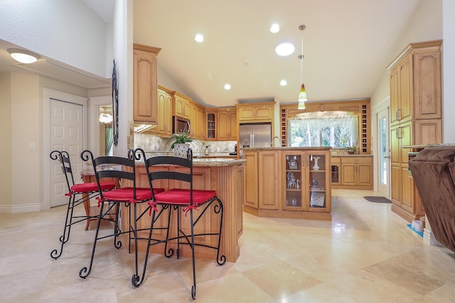 kitchen with stainless steel appliances, tasteful backsplash, light stone countertops, vaulted ceiling, and a breakfast bar