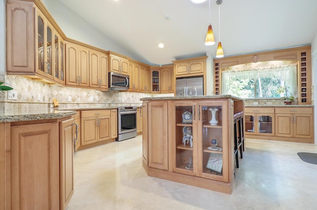 kitchen with lofted ceiling, a kitchen island, stainless steel appliances, hanging light fixtures, and light stone counters