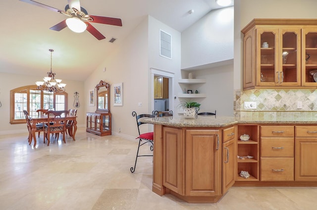 kitchen with ceiling fan with notable chandelier, decorative light fixtures, backsplash, high vaulted ceiling, and a breakfast bar area