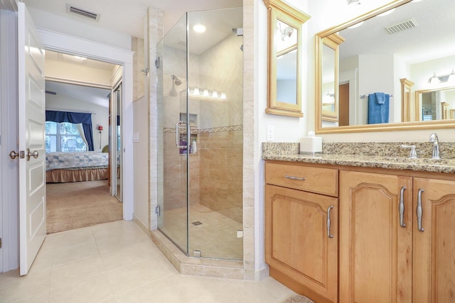 bathroom with a shower with shower door, vanity, and tile patterned flooring