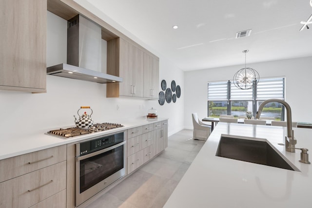 kitchen featuring sink, light brown cabinets, wall chimney exhaust hood, and appliances with stainless steel finishes