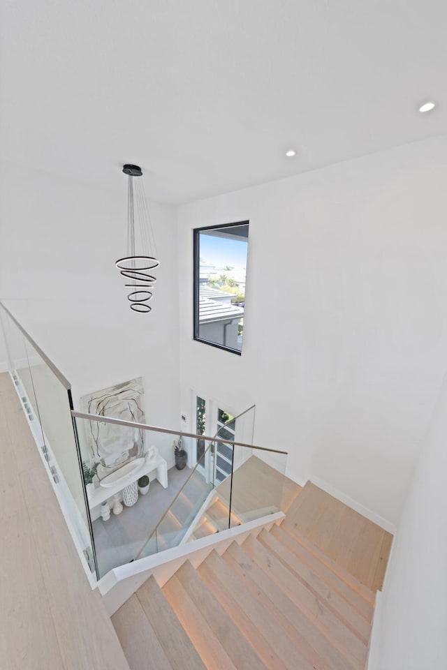 staircase featuring hardwood / wood-style flooring and a notable chandelier