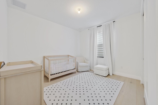 bedroom featuring hardwood / wood-style floors and a crib