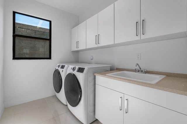 laundry area with washer and clothes dryer, light tile patterned flooring, cabinets, and sink