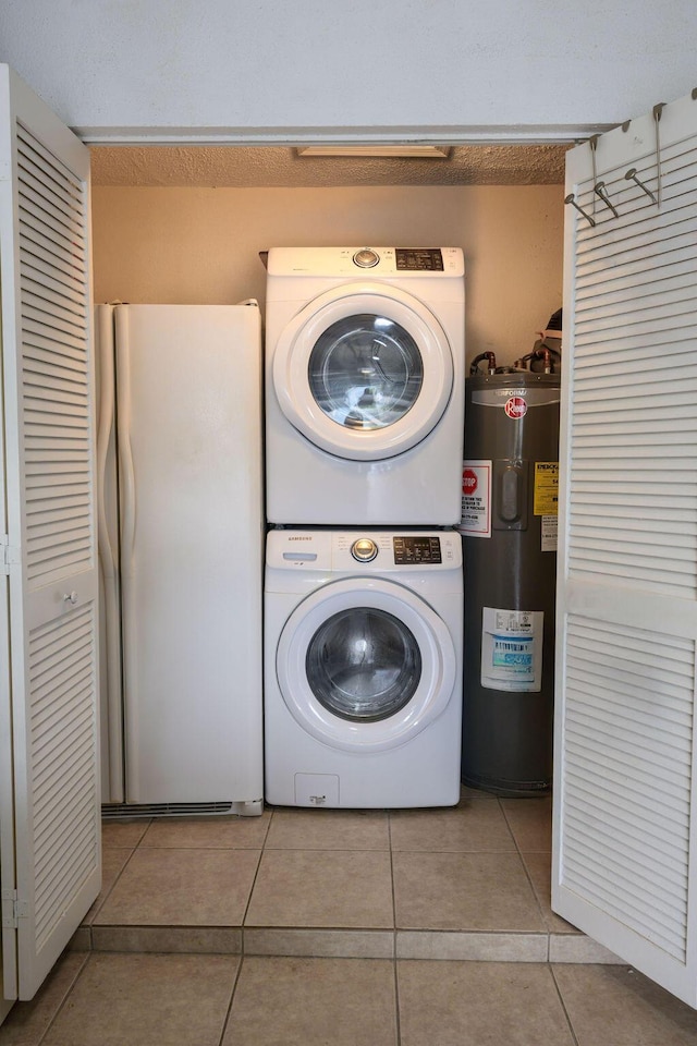 laundry room featuring light tile patterned flooring, electric water heater, and stacked washer and clothes dryer